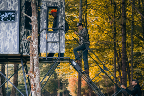 3 men climbing into a blind stand