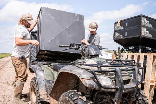 two men placing a feeder on a four-wheeler 
